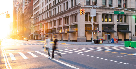 People walking across the empty street intersection on Fifth Avenue past boarded up buildings during the coronavirus lockdown in New York City