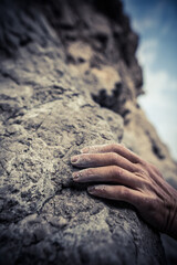 Adult male handholding on to a rock