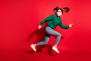 Profile side photo of brunette tails pretty lady jump run copyspace wear jeans green sweater mask pandemic isolated on red color background