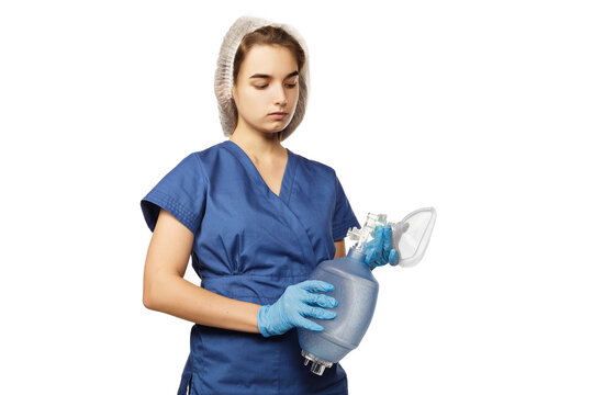 Young beautiful woman doctor in blue surgical gown and gloves holds in hands Am-bu bag for artificial lung ventilation isolated on white background