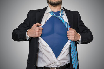 Strong businessman as superhero is opening his shirt.