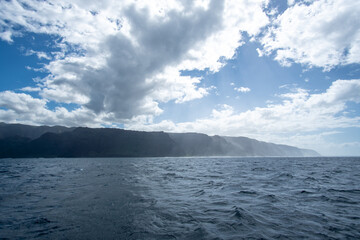 View of a misty Na Pali Coast of the Hawaiian Island, Kaua'i from a boat. The coastline got its name from the obvious towering sea cliffs that rise dramatically over the Pacific Ocean.