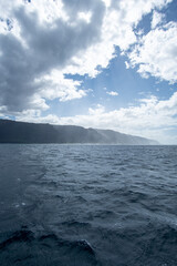 Fototapeta na wymiar View of a misty Na Pali Coast of the Hawaiian Island, Kaua'i from a boat. The coastline got its name from the obvious towering sea cliffs that rise dramatically over the Pacific Ocean.