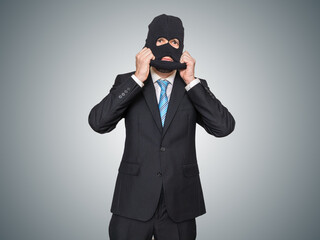 Businessman in suit is wearing balaclava as thief or burglar.