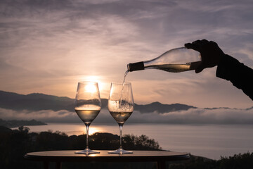 Pouring White wine in a glass on a panoramic rooftop at sunset