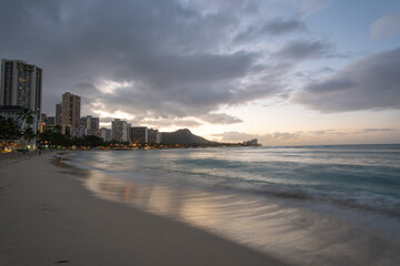 Waikiki, Honolulu, Oahu, Hawaii - February 9, 2019: Long exposure shot of Waikiki Beach during the early morning hours as the sun is rising behind the famous volcanic crater, Diamond Head.