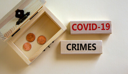 Concept words 'COVID-19 crimes' on blocks on a beautiful white background, small chest with coins....