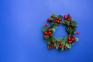 Christmas holidays composition with christmas decorations, red berries branches on blue background with copy space, top view