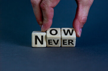 Now or never. Male hand flips wooden cubes and changes the inscription 'never' to 'now' or vice versa. Beautiful grey background, copy space.