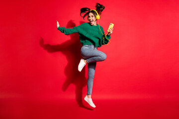 Fototapeta na wymiar Full length photo of charming young woman dressed green knitted sweater headset dancing jumping isolated red color background