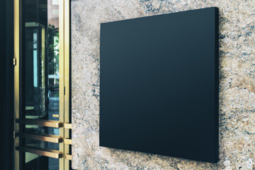 Black square sign with blank space for your logo on the marble wall of a modern shopping center,...