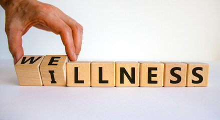 Wellness or illness. Male hand flips wooden cubes and changes the inscription 'illness' to 'wellness' or vice versa. Beautiful white background, copy space. Lifestyle concept.