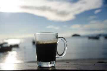 Close up Coffee cup on old wood table and view of tropical beach