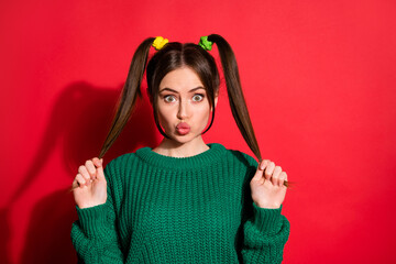 Portrait of pretty cute girl blow kiss hold tails dress green sweater isolated on red color...