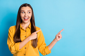 Portrait of cute optimistic brunette lady pointing empty space wear yellow cloth isolated on teal...