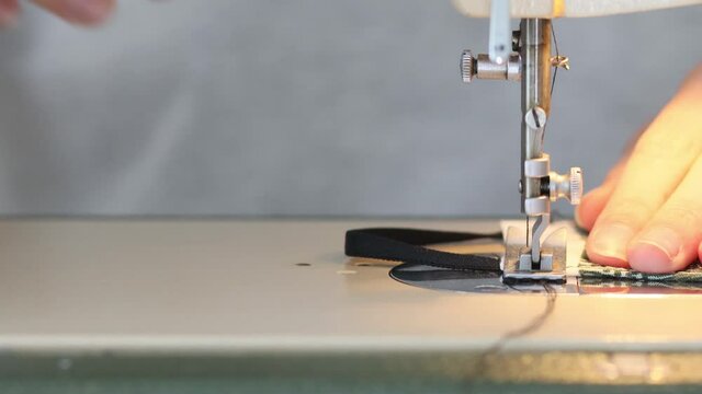 Girl sewing protective medicine mask on sewing machine at home to prev
