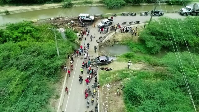 Aerial view overlooking a crowd and a rescue team aiding injured people, due to a car accident, in Africa - static, drone shot