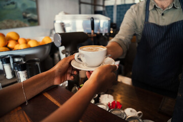 Male waiter handing woman freshly brewed coffee in funky cafe 