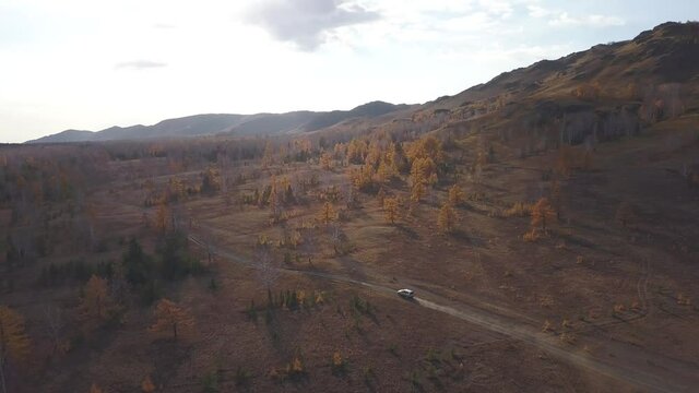 Aerial view car off-road adventures on the Ural Mountains. Jeep driving on country forest road goes around obstacle. Autumn travel
