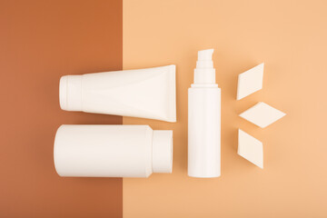 Top view of beauty products for daily skin care and make up sponges for make up application on brown and beige background