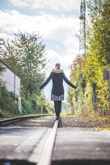 Young pretty girl is balancing on railroad, concept for travelling
