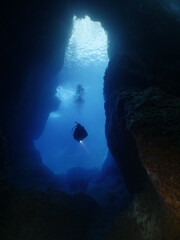 Obraz premium cave diving underwater scuba divers exploring caves and having fun ocean scenery sun beams and rays background