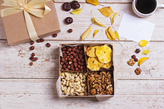 A box of nuts and dried fruits on old wooden background. hazelnut, cashew, dried daddy, dried pineapple. A gift on the day of the anniversary.