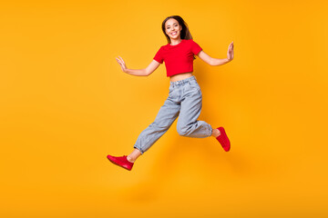Fototapeta na wymiar Full body photo of jumping lady making step wear red crop top jeans shoes isolated yellow color background
