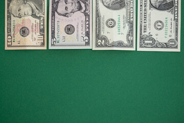 American money flat lay on a green background. 10, 5, 2 and 1 dollar notes. Top view.