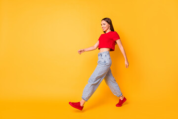 Fototapeta na wymiar Profile photo of lady traveler walking down street wear red crop top jeans shoes isolated yellow color background