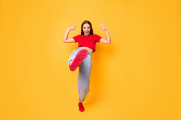 Full length photo of crazy lady dancing raise leg in front of camera wear red crop top jeans isolated yellow color background