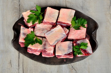 Raw meat ribs on a black silver plate, gray wooden background. Raw Organic Beef Short Ribs