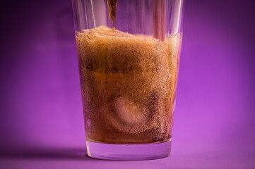 detail of fizzy and carbonated cola drink on purple background