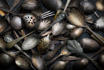 Old tarnished silverware, including spoons, fork, and collector items.