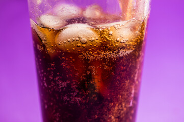 detail of fizzy and carbonated cola drink on purple background