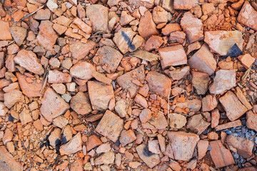 A pile of old broken red clay brick rubble after demolition of an old building lies on the ground on a building site.