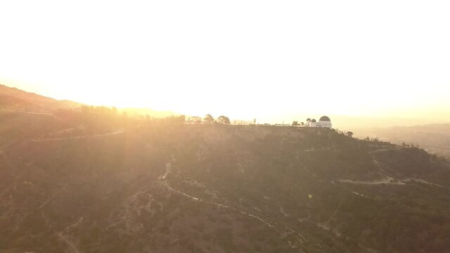 AERIAL: A drone shot of the Griffith Observatory and LA Downtown at Sunset