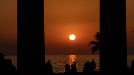 people in silhouette by the sea at sunset