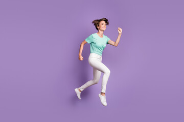 Fototapeta na wymiar Full size profile photo of nice pretty girl jumping hands fists wear white sneakers trousers blue t-shirt isolated on violet background