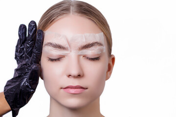 Master makes an eyebrows correction to a young woman. Henna coloring procedure in a beauty salon....