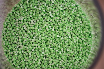 Obraz premium Green plastic polymer granules in the cap