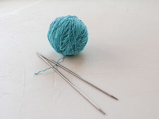 cotton thin thread and knitting needles for knitting on a white background