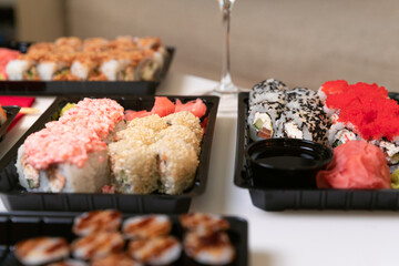 A set of colorful sushi set on a white table with wine in a cozy room.