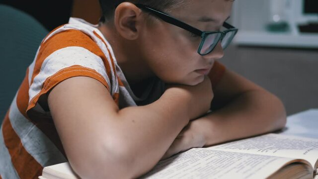 Inquisitive, a Serious Boy with Glasses is Reading an Interesting Book at Home