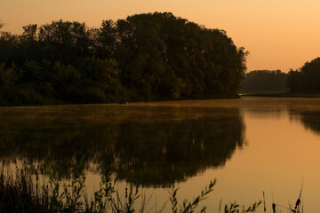 Fototapeta na wymiar a soft orange sunrise over a calm lake overgrown with water lilies