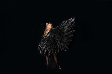 Obraz premium beautiful blonde girl in a black suit with black wings on a black background