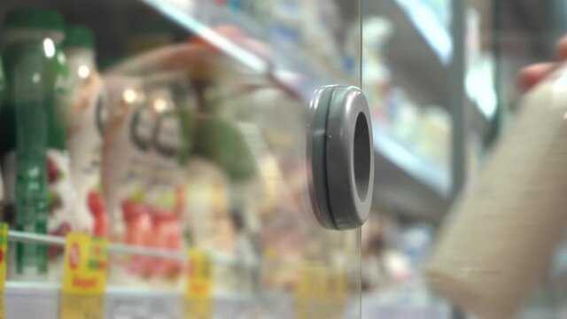 Close-up of a young male consumer's hand taking a plastic bottle of fresh milk drink from a refrigerated shelf in a store. Lifestyle concept.