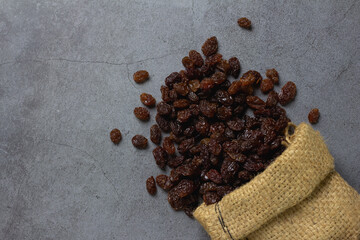 Dried raisins in burlap bagl on table