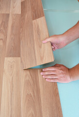 Wood laminate flooring installation: a handyman is laying the laminate flooring plank on the the...