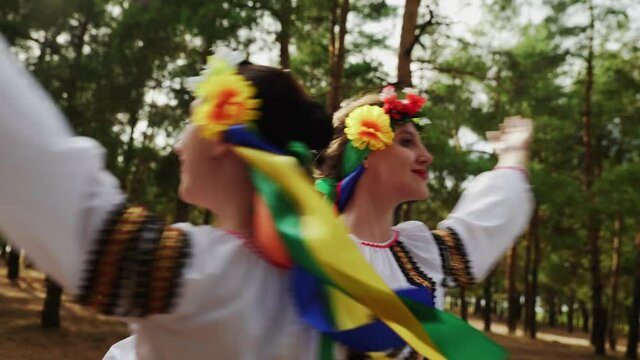 CLose up of two women in traditional costumes are dancing Ukrainian national dances